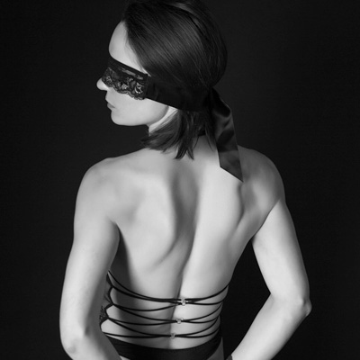 An elegant boudoir portrait of a blindfolded, cuffed woman.